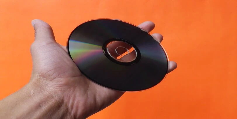 A man holding a disc on an orange background.